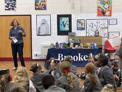 Mrs Elford of Brookes UK School teaching students about the Harvest festival donations